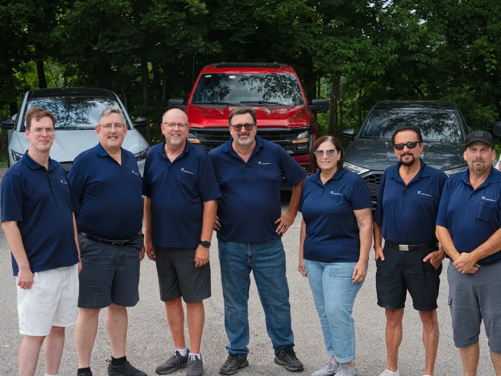 The Reliable Deliveries team stands together in front of company vehicles, a trusted Niagara courier company.
