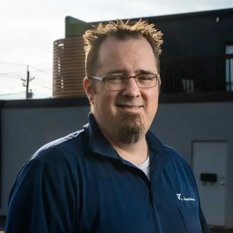 Jason, Reliable Deliveries driver, smiling outdoors in company polo shirt.
